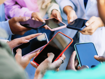 Many hands holding phones